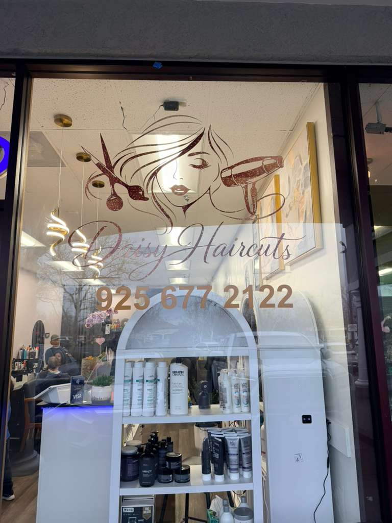 Drissy Haircuts storefront window with salon logo, contact number, and hair care products on display.