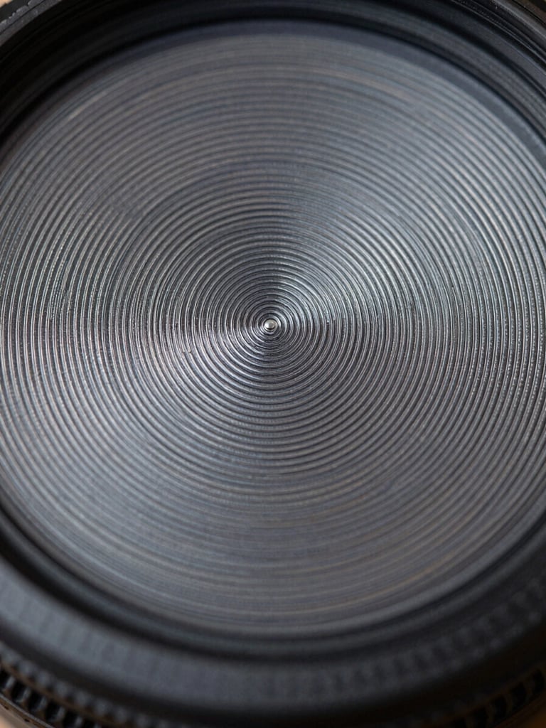 Extreme close-up of a biometric sensor surface under cool even studio light, fine concentric scan rings and metallic contact grid in sharp focus, dark background with geometric precision, no human elements