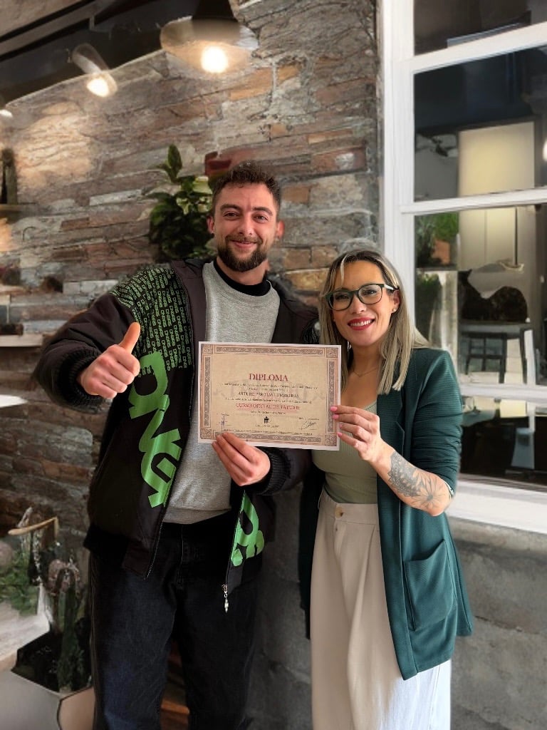 Alumno junto a Rebeca Pereira durante la entrega de diploma tras completar su formación de tatuaje