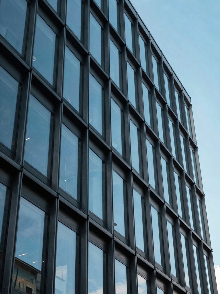 Architectural detail of modern steel and glass building facade reflecting a clear blue sky