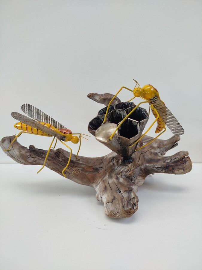 Handmade metal yellow jackets sculpture on driftwood base with a honeycomb nest.
