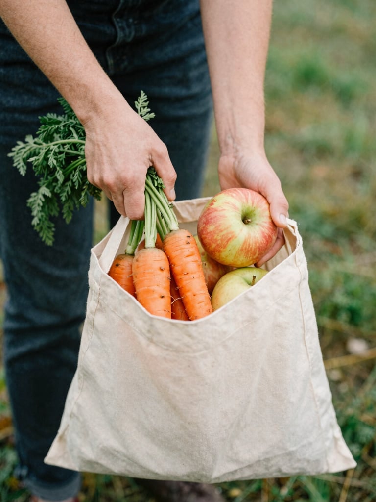 Warm hands of a volunteer placing fresh organic carrots and apples into a clean canvas bag, soft natural Pacific Northwest daylight, 35mm film look.