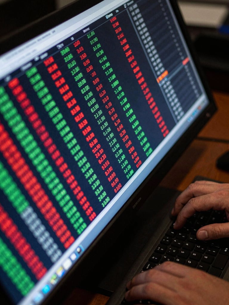 Close-up overhead of a trading terminal screen, electric green and red ticker rows mid-scroll, hands resting on keyboard edge, cool blue-white screen glow, dark desk surface visible at corners, tight frame on the live data