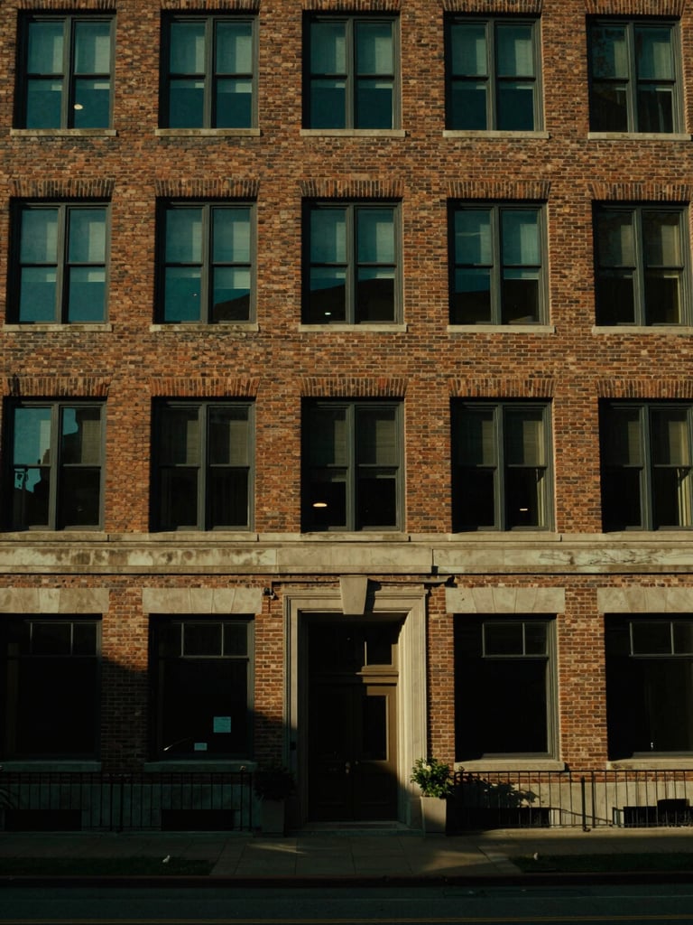Cinematic wide shot of a historic brick corporate headquarters, dramatic low-key side-lighting, rich emerald shadows, medium format film look