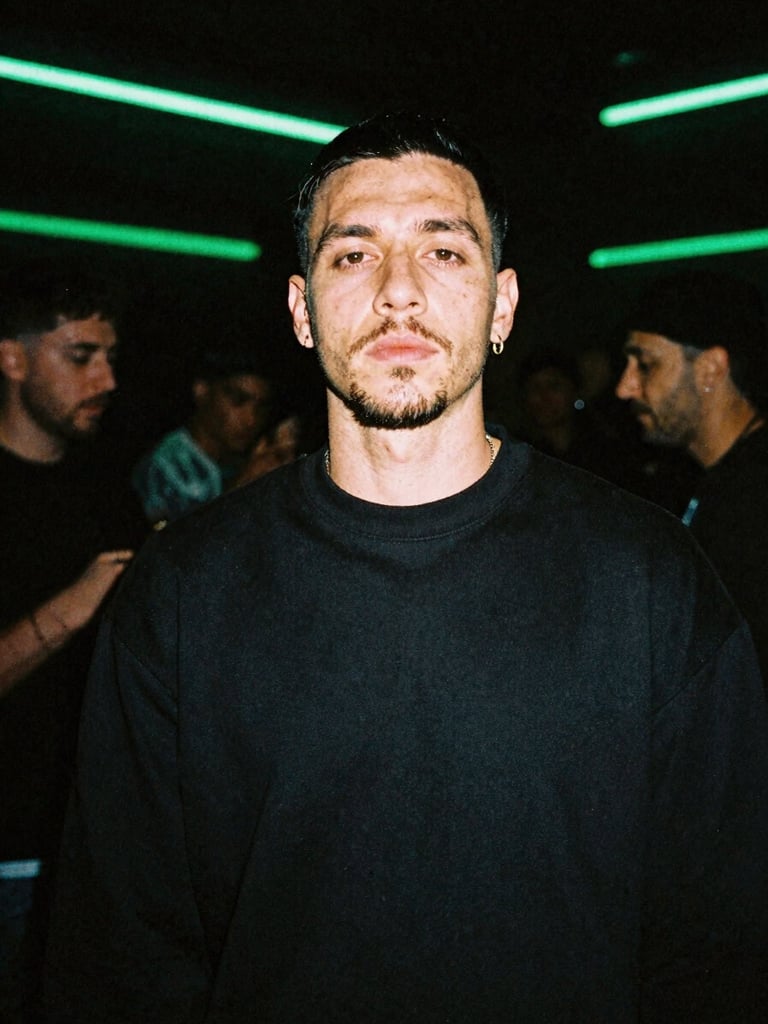 Gritty flash-exposed portrait of a UK drill artist backstage in a dimly lit venue, electric neon green ambient glow, deep shadows, 35mm film grain