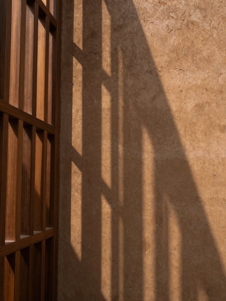 Serene architectural crop of the Kolkata sanctuary, natural light filtering through a wooden screen casting long linear shadows on a raw clay wall, minimalist composition.