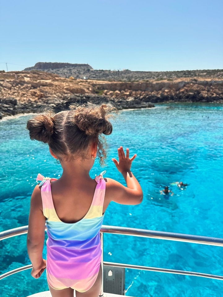 Child waving at mermaids swimming in the sea during a boat tour Cyprus