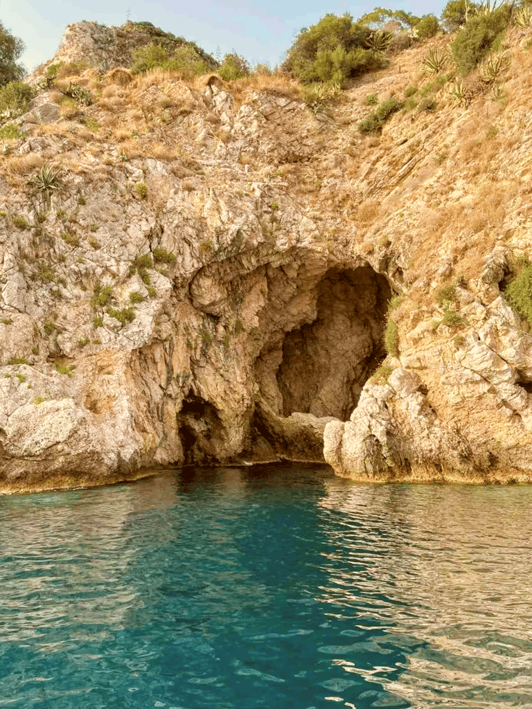 a boat is coming out of a cave in the mountains