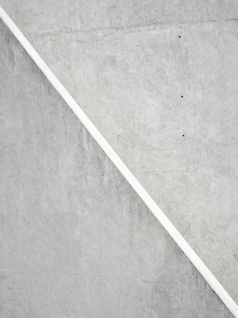 Close-up of raw board-formed concrete texture, sharp diagonal shadow, minimalist architectural detail, high contrast, 35mm