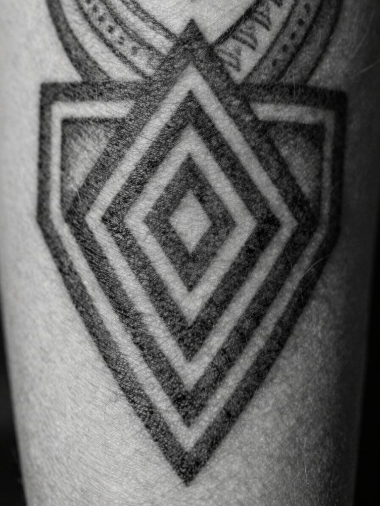 Extreme macro shot of a fresh black ink tattoo on skin, showing sharp geometric patterns and deep chiaroscuro lighting, high contrast, black and white.