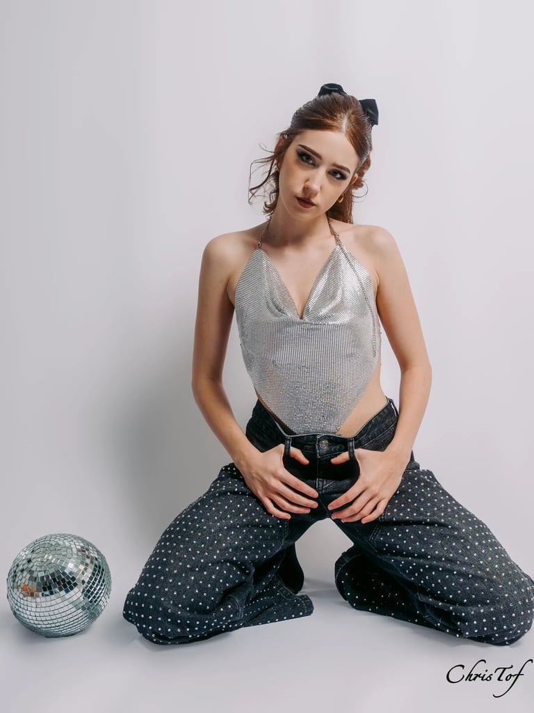 Portrait femme posant en top dos nu argenté brillant et jean à strass en studio à Perpignan.