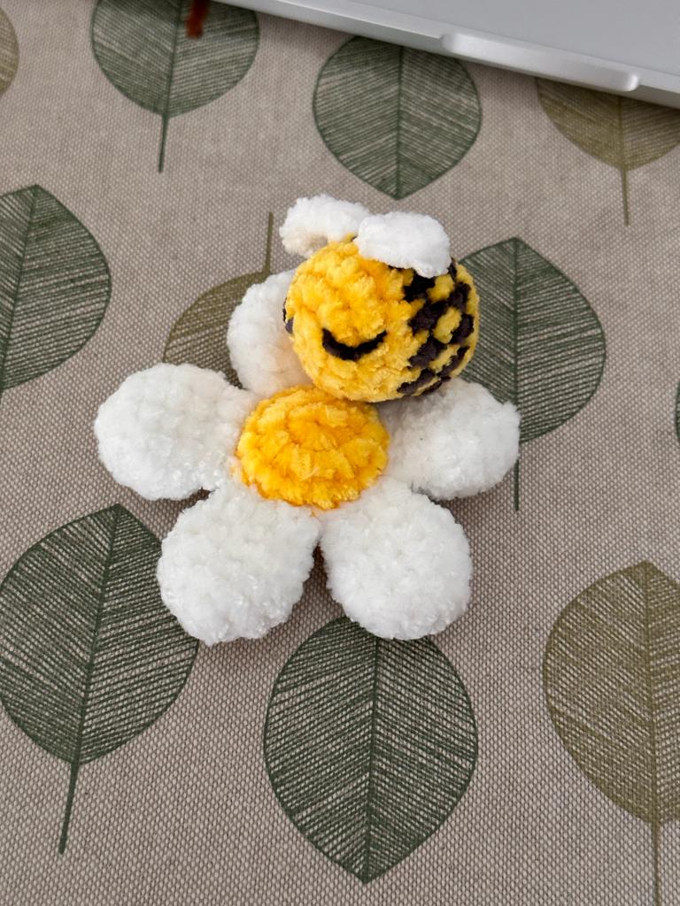 a handmade amigurumi stuffed daisy with bee toy 
