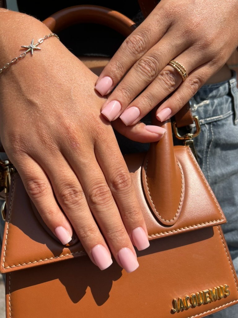 a woman's hands with a brown leather handbag