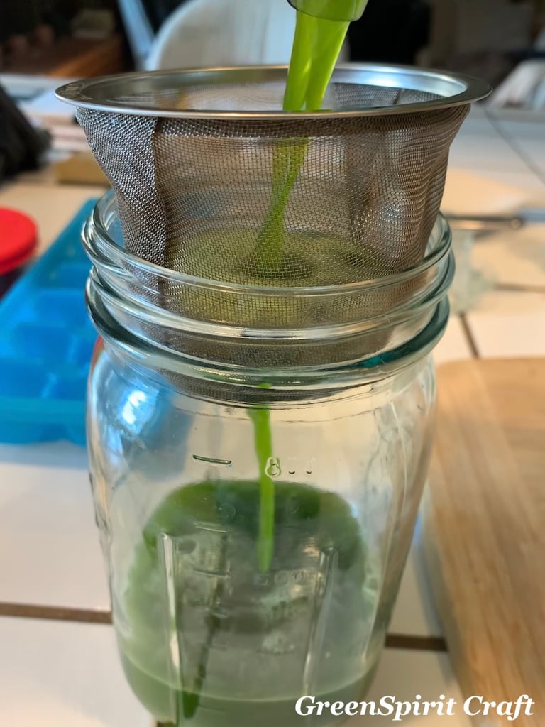 a bright green herbal juice being poured through a strainer into a clear glass jar