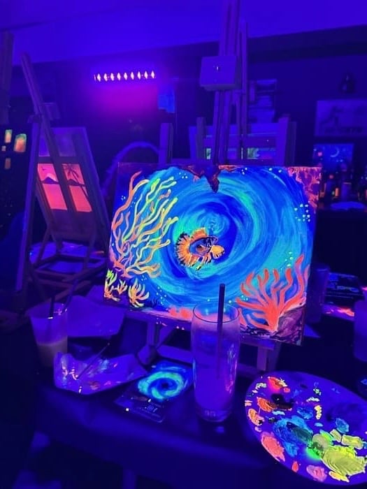 Peinture néon phosphorescente d’un poisson tropical et d’un récif corallien sous lumière UV à Strasb