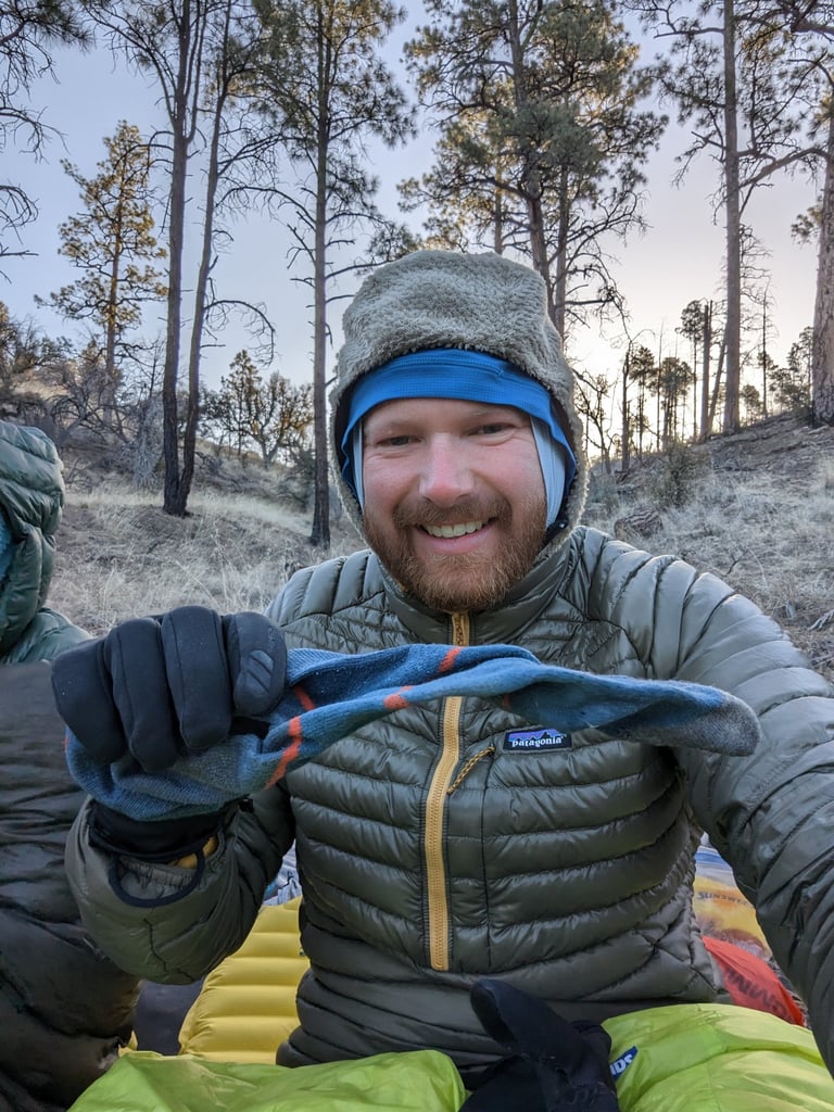 Moose holds a frozen solid Darn Tough sock in a ponderosa forest on the Grand Enchantment Trail.
