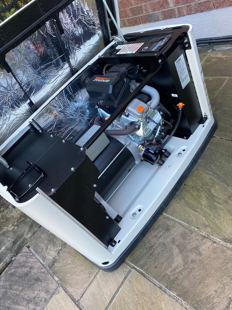 Internal engine components of an open Generac home standby generator installed on a stone patio.