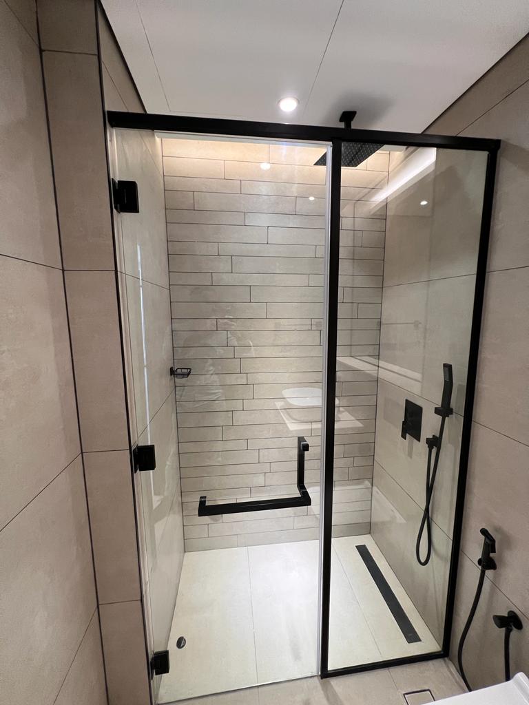 Modern walk-in shower partition with matte black stainless steel frame and tempered glass.