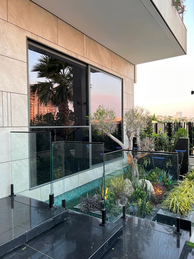 Frameless glass garden fencing with stainless steel spigots bordering a green lawn.