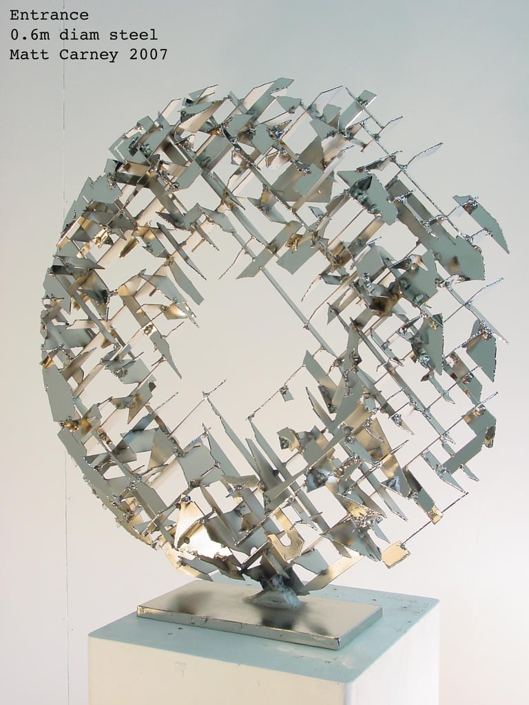 a silver cross-hatched circle sculpture side view
