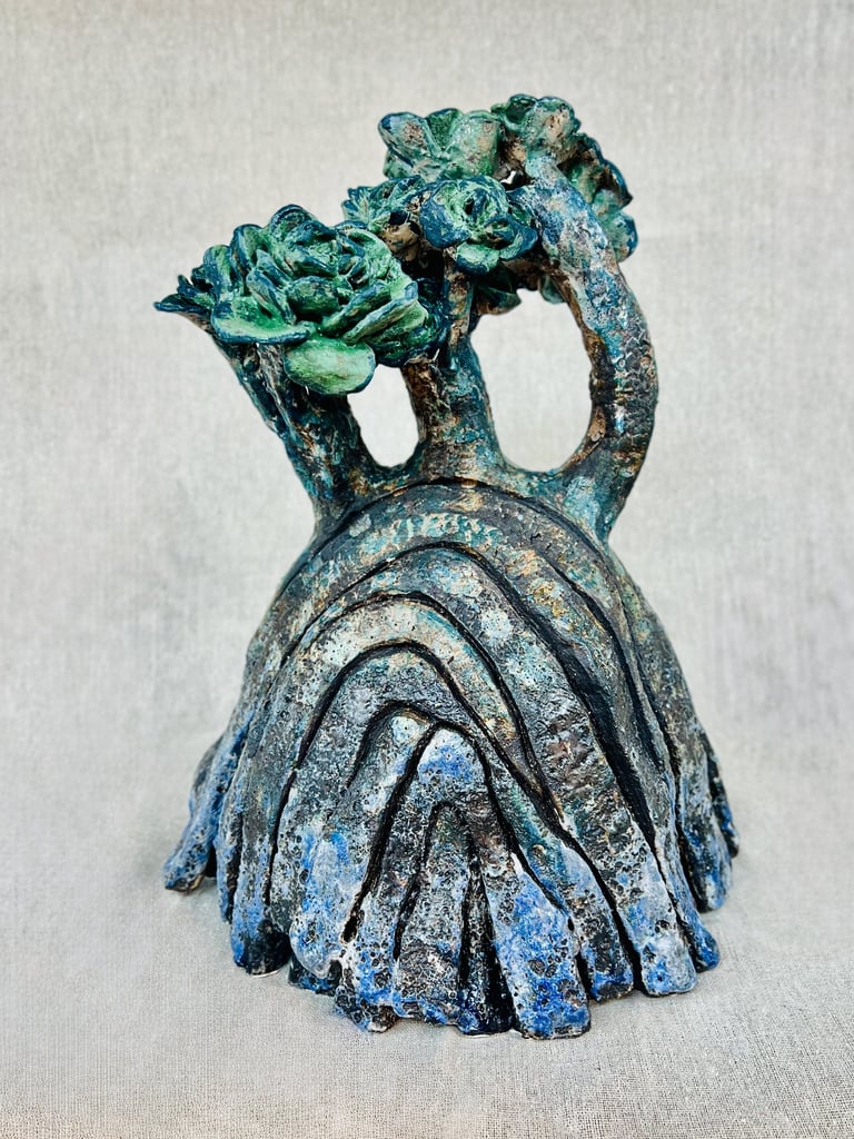 A ceramic plant-like sculpture glazed in green blue and brown tones
