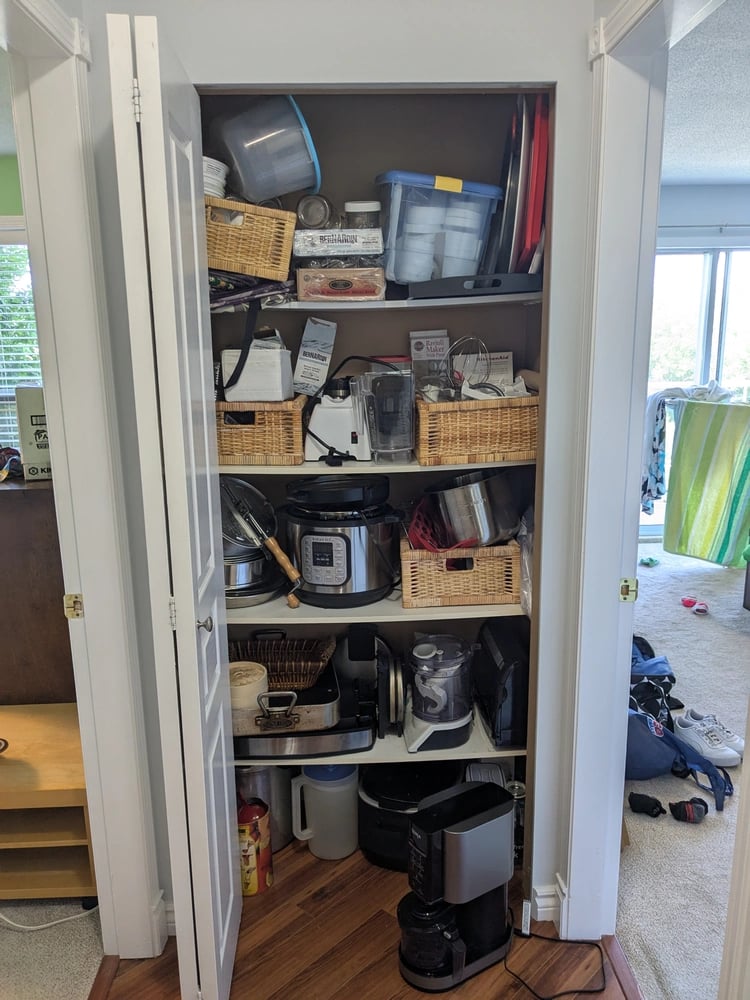 Kitchenware closet with bowed melamine shelving and disorganized clutter
