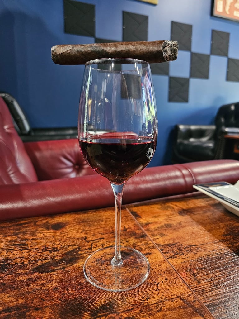 cigar resting on top of wine glass filled with red wine