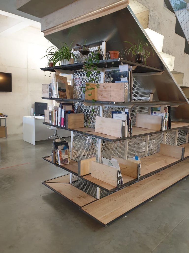 a wooden and steel library installed under a staircase in a mediatheque