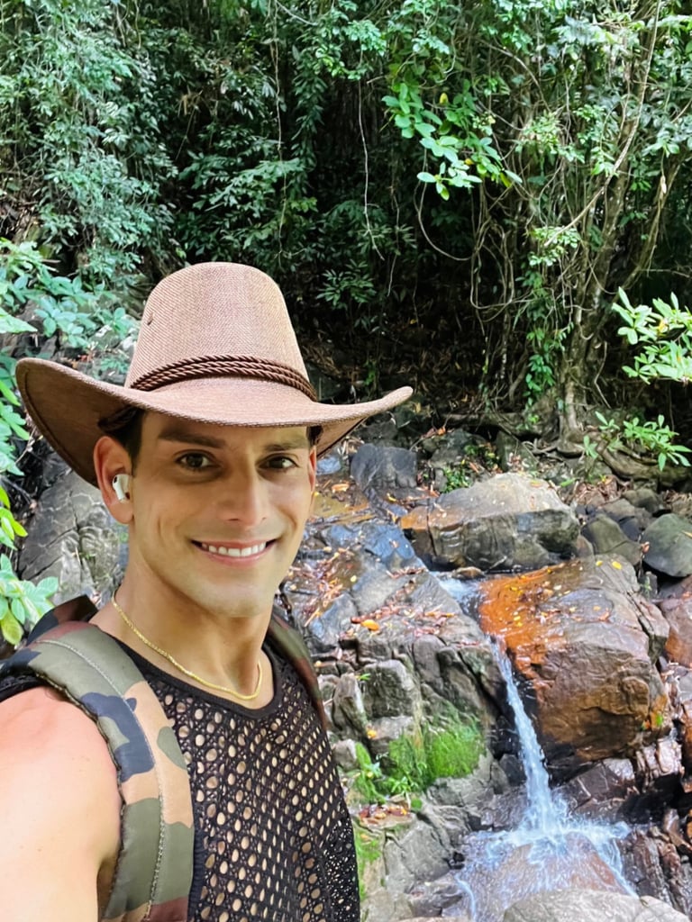 Travel writer Rick Silvia smiles at the camera wearing a cowboy hat in front of a waterfall