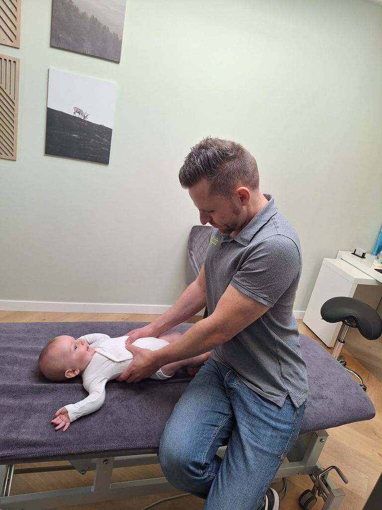 een man geeft een manuele behandeling aan een baby in zijn buik