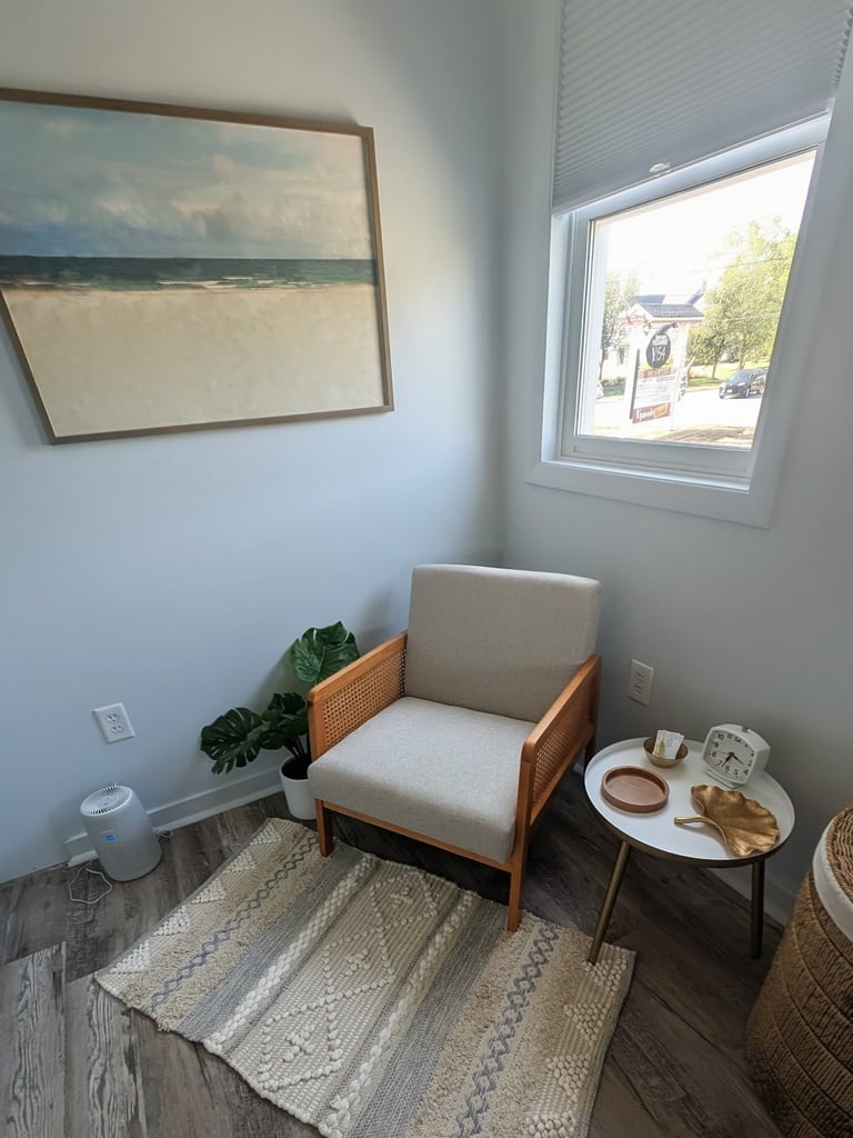 a waiting area with a chair and a table with a painting on the wall