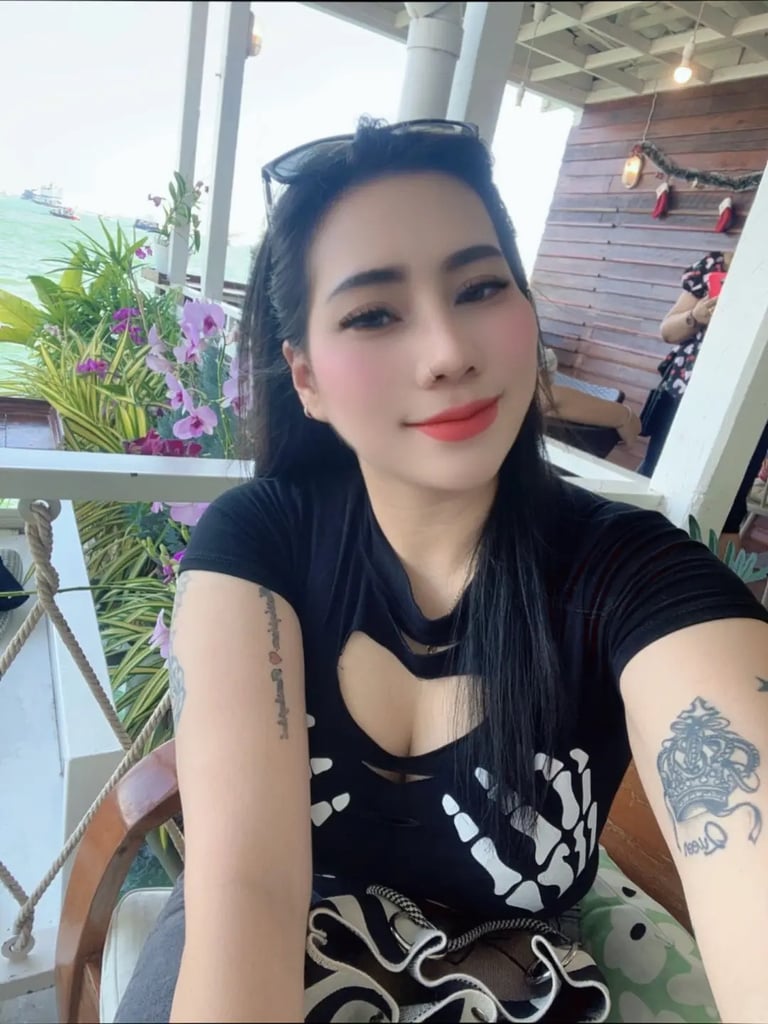 Lady wearing a black dress and tattoos showing on arms 