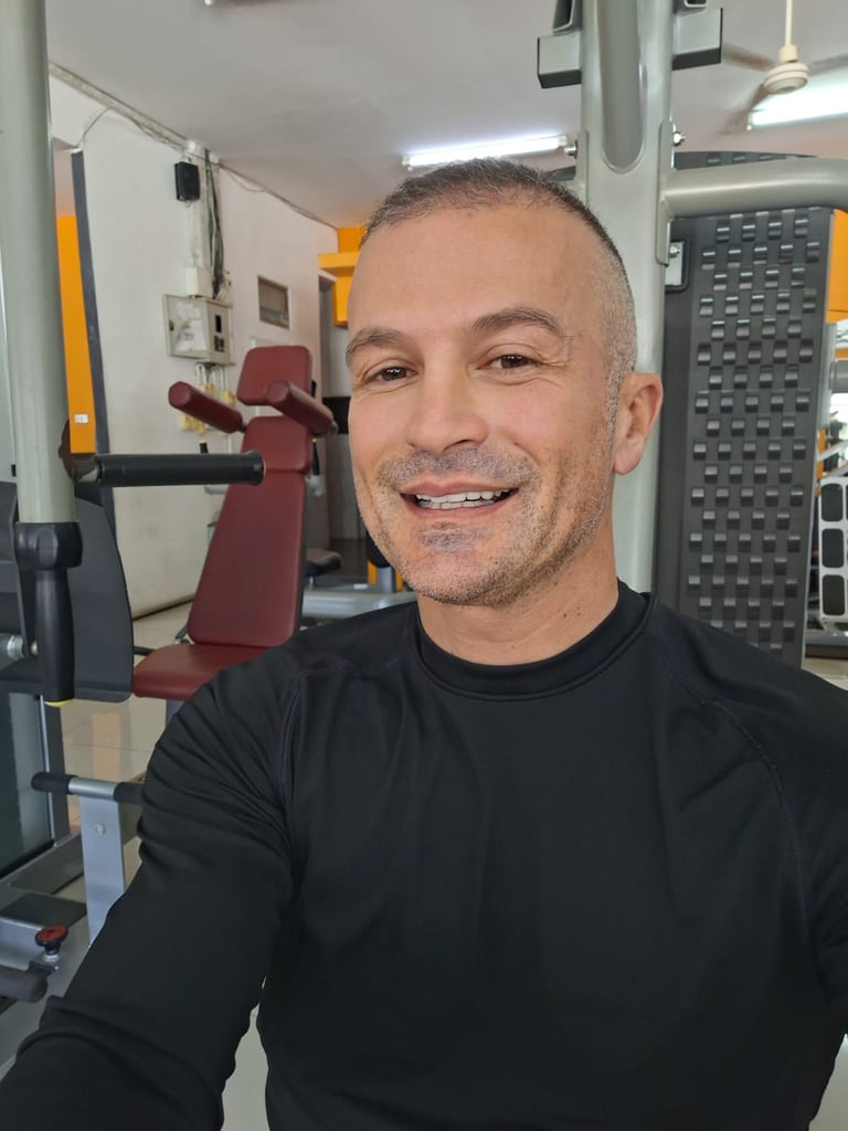 Male therapist wearing black top sitting in a gym