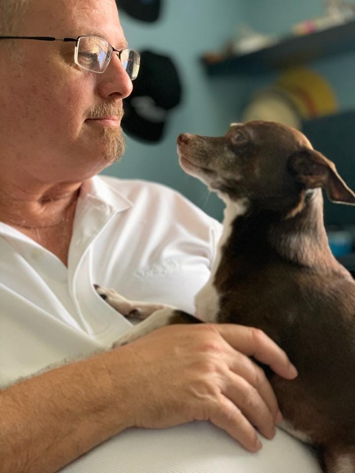 a man in a white shirt is holding a dog
