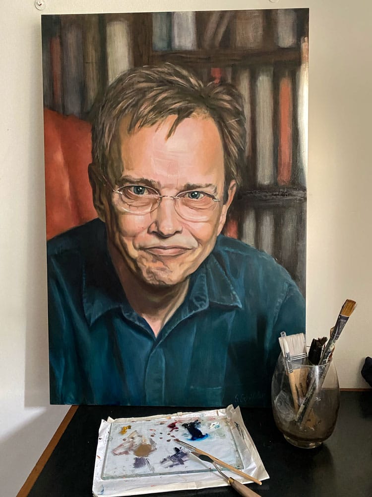 Oil painting and brushes of man with glasses by bookshelf.