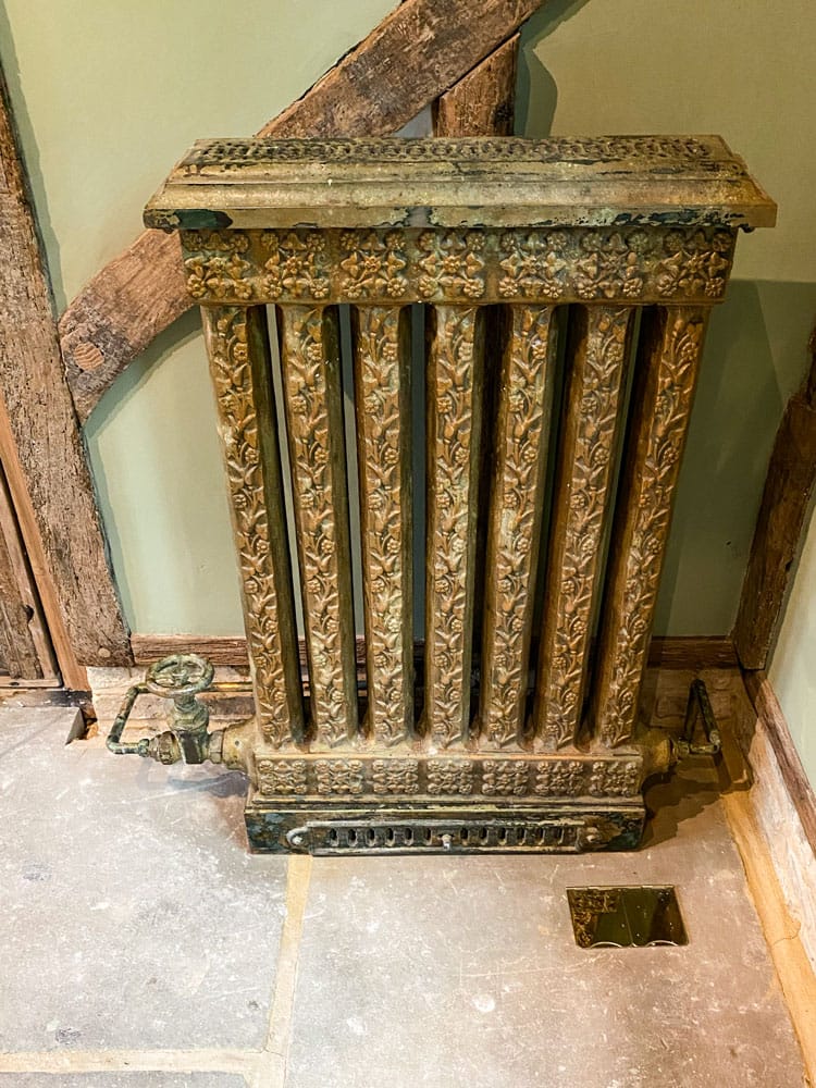 Vintage radiator with layers of paint applications and a faux painted pipe to match.