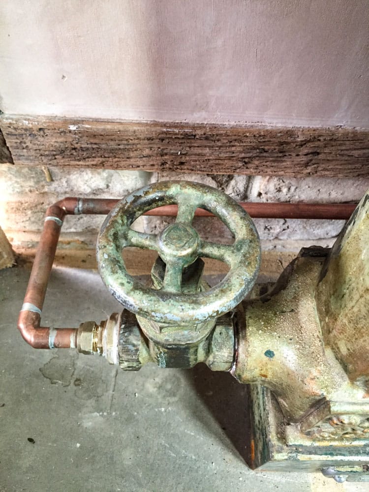 Close-up on a painted radiator valve and a new copper pipe on antique plaster wall