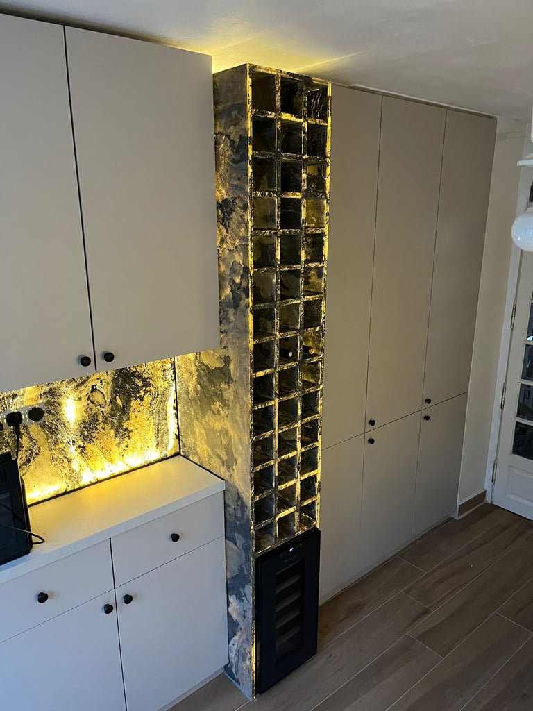Modern minimalist kitchen featuring backlit gold marble backsplash and integrated wine rack cabinets.