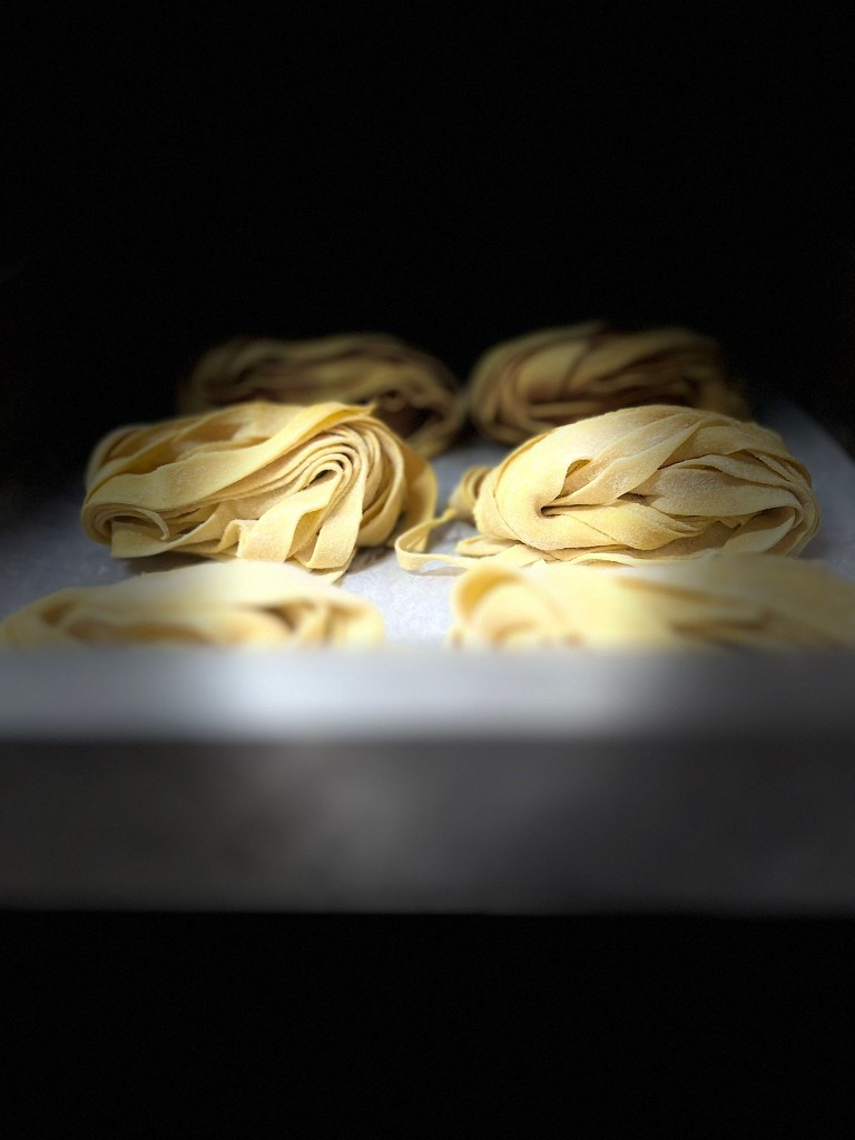 Frisch zubereitete hausgemachte Tagliatelle auf einem traditionellen Holzbrett.
