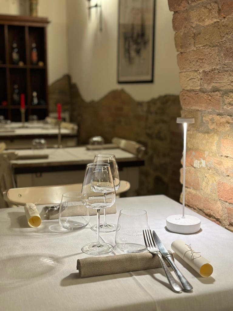 Tavola apparecchiata con calici di vino in sala con mattoni a vista - Cozy indoor table setting and 