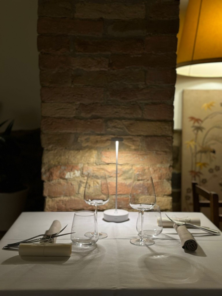 Tavola apparecchiata con calici di vino in sala con mattoni a vista - Cozy indoor table setting and 