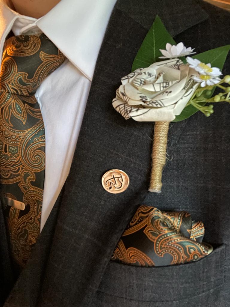 a man in a suit and tie with a flower made from music paper