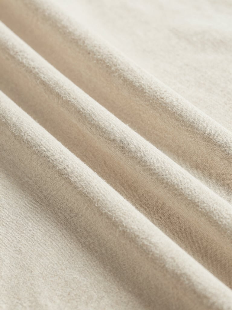 Close-up of soft beige linen fabric draped elegantly, showing fine weave texture, bright natural lighting