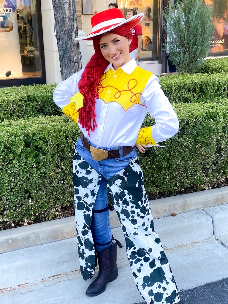 A smiling woman wearing a Jessie from Toy Story costume with a cow print outfit and red cowgirl hat.