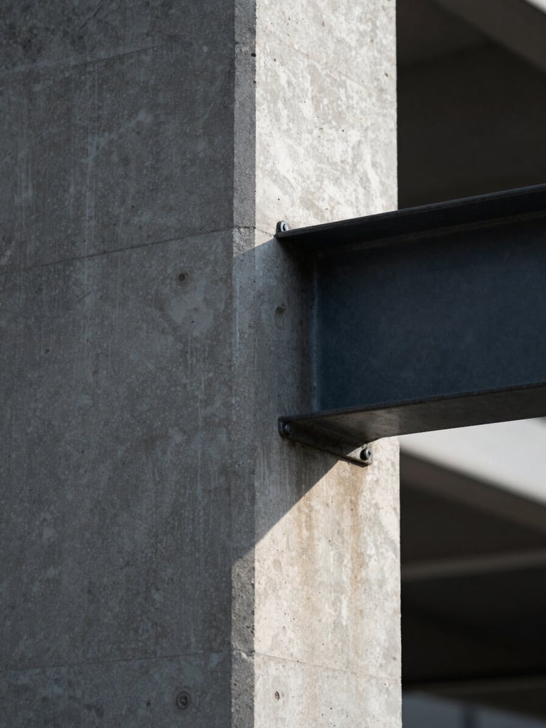 Tight macro shot of a cast concrete structural pillar meeting a dark steel beam, sharp geometric shadows, cool natural light, minimal composition.