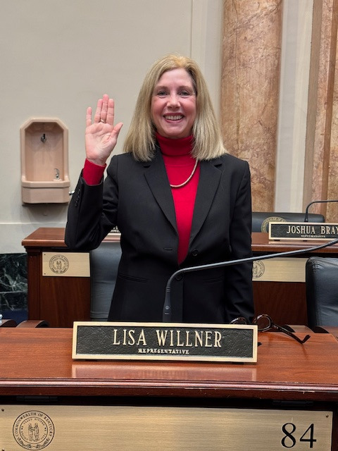 a woman in a suit and red top standing in front of a microphone