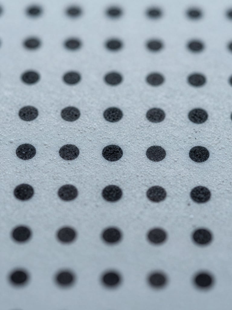Extreme close-up of a printed substrate surface, ink dots and texture sharply resolved under cool studio daylight, color accuracy visible at material level, tight macro framing from directly above