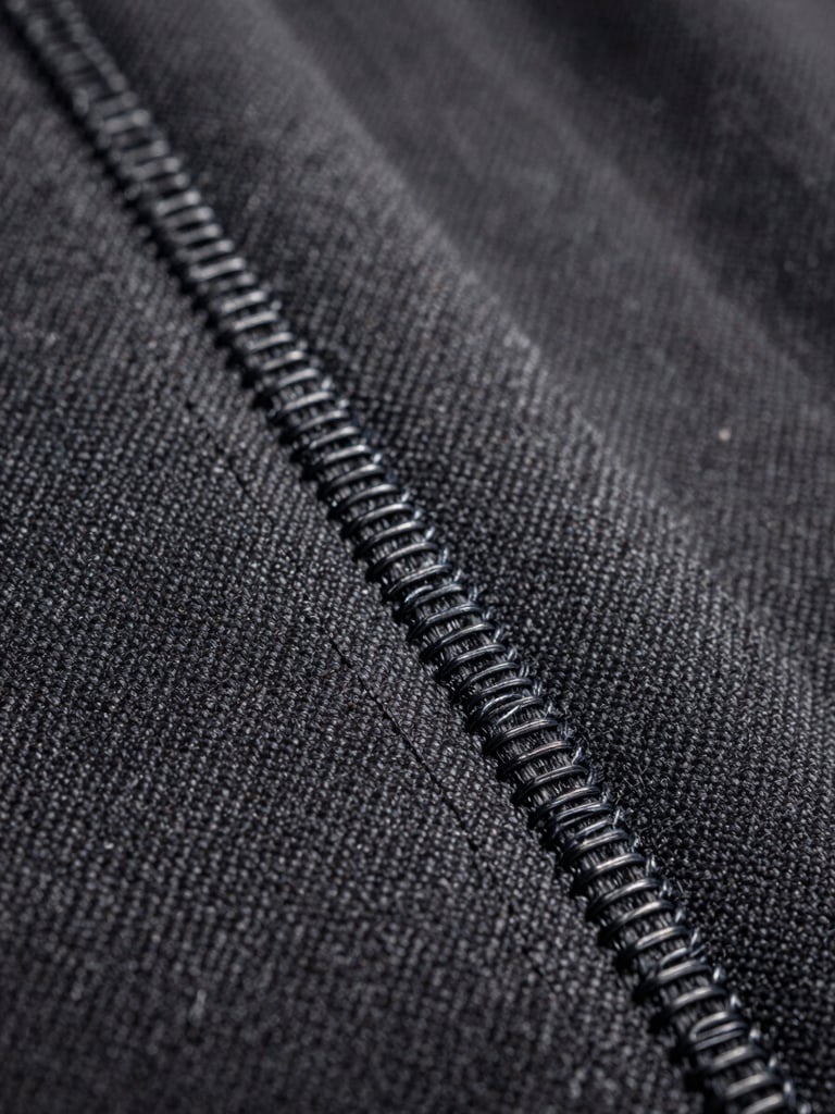 Macro shot of a patch border showing the tight overlock merrow stitch on heavy canvas, side lighting.