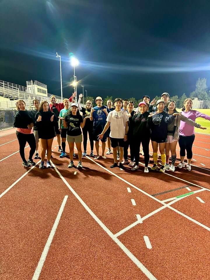 a group of people standing on a track with Coach Ray Z after barefoot training class