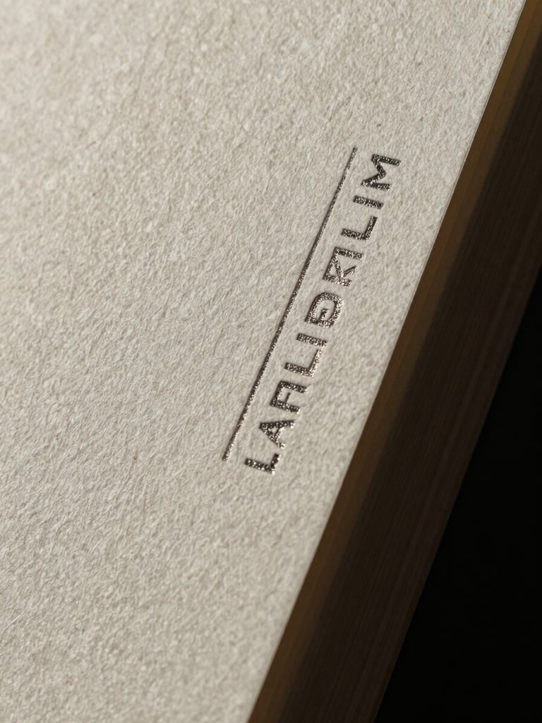 Extreme macro studio photograph of thick textured paper stock with deeply debossed metallic foil stamping, razor-sharp edges, high-contrast dramatic shadows.